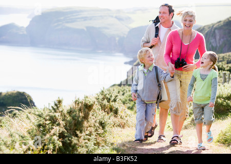 Family walking on cliffside path holding hands and smiling Stock Photo