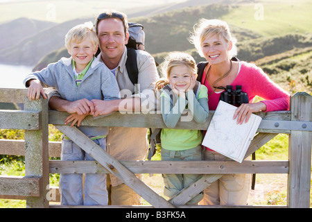 Family on cliffside path leaning on fence and smiling Stock Photo
