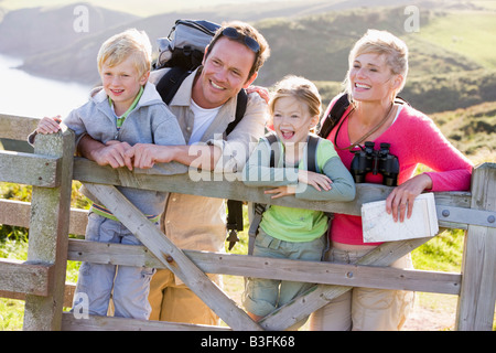 Family on cliffside path leaning on fence and smiling Stock Photo