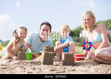 Family on beach making sand castles smiling Stock Photo