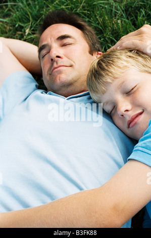 Father and son lying outdoors sleeping Stock Photo