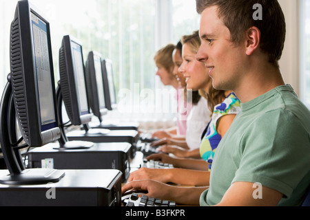 Four people sitting at computer terminals (depth of field/high key) Stock Photo
