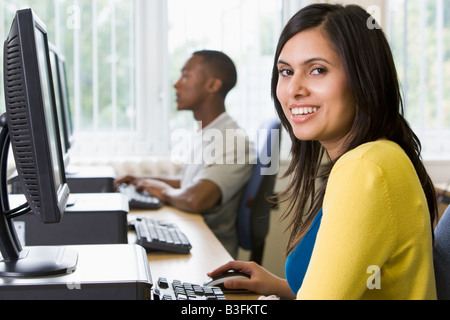 Woman sitting at a computer terminal with man in background (selective focus/high key) Stock Photo