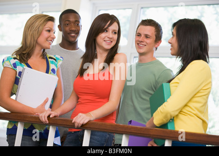 Five students in corridor leaning on railing with notebooks Stock Photo
