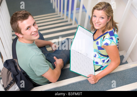 Two students sitting on staircase with notebooks (selective focus) Stock Photo