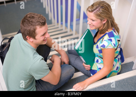Two students sitting on staircase with notebooks (selective focus) Stock Photo