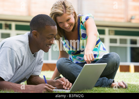 Two students outdoors on lawn with laptop Stock Photo