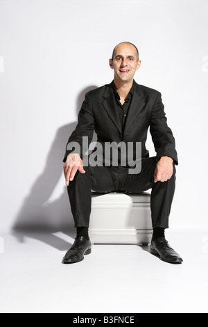 Man in a busines suit sat on a brief case Stock Photo