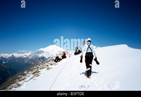 Mountaineers on summit of Mt Viautau (3820m). The twin summits of Mount Elbrus (5642m) in the background. Russia/North Caucasus Stock Photo