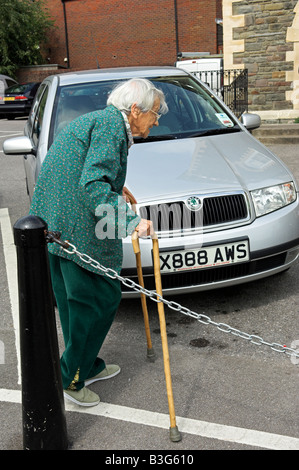 Active elderly English 92 year old woman walking alone in car park with canes Stock Photo