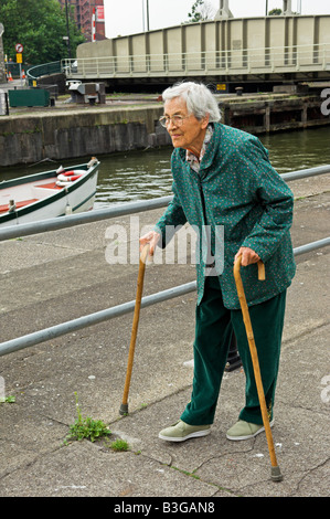 Active elderly English 92 year old woman walking with two canes by Bristol City docks Stock Photo