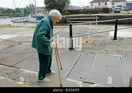 Active elderly English 92 year old woman cautiously walking with two canes by Bristol City docks Stock Photo