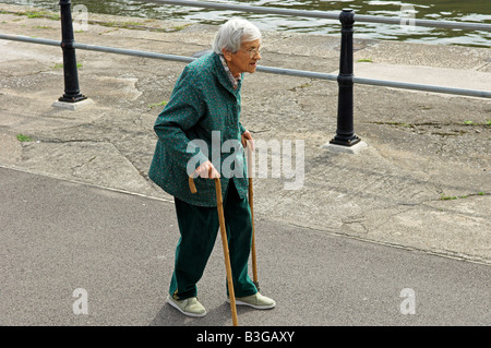 Active elderly English 92 year old woman walking with two canes by Bristol City docks Stock Photo