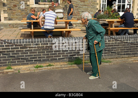 Active elderly English 92 year old woman walking with two canes outside a pub Stock Photo