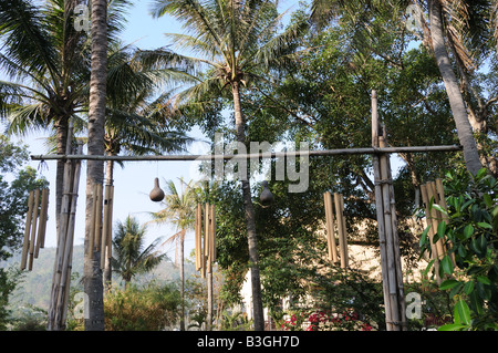 Wind chimes hanging on bamboo poles at a traditional Longhouse Hotel on the shores of Lak Lake Vietnam Stock Photo