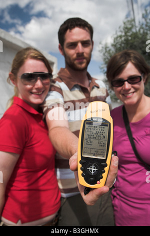 Tourists holding a GPS device showing 00.00.00 latitude at the middle of the earth near Quito in Equador. Stock Photo