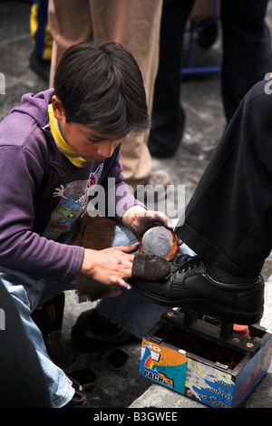 A local boy cleaning shoes on the street in Latacunga in Ecudaor Stock Photo