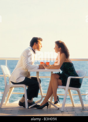 Young couple on holiday. Having a drink on waterfront terrace. Stock Photo