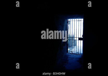 one secluded prison cell door in dark black room Stock Photo