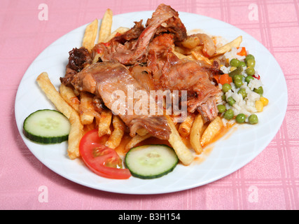 Traditional Greek rabbit stifado or stew at a taverna in Greece served with french fries rice and vegetables Stock Photo