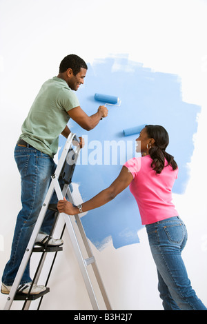 Smiling African American male and female couple painting wall blue Stock Photo