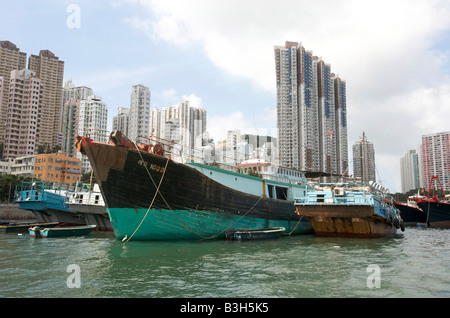 Fishing boats moored in Aberdeen fishing village with high-rise apartment blocks behind Hong Kong Hong Kong Stock Photo