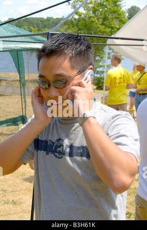 Intense Asian American man age 23 talking on his cell phone. Dragon Festival Lake Phalen Park St Paul Minnesota USA Stock Photo