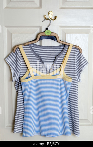 Two ladies size 12 summer t shirts hanging on a hook on the back of a white door Stock Photo
