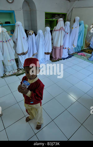 muslim children praying at the charity  sponsored islamic school in slum neighbourhood in kuta , bali , indonesia Stock Photo