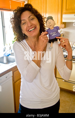 A 50 year old woman smiles happily while holding a Fifty and Fantastic doll joke gift at her birthday party in Mission Viejo Cal Stock Photo