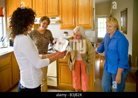 A 50 year old woman smiles happily while holding a Fifty and Fantastic doll joke gift at her birthday party in Mission Viejo Cal Stock Photo