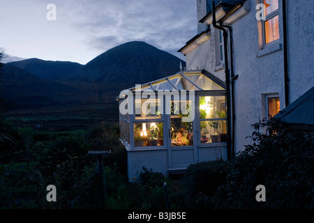 Resident of Swordale House sits reading in her conservatory of overlooking Beinn Na Caillich, nr Broadford, Isle of Skye Stock Photo