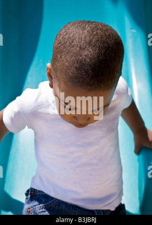 A 2 year old African- American boy plays on a slide at a public playground in Cathedral Square Park in Milwaukee, WI. Stock Photo