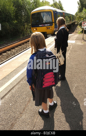 Young girls waiting for their train on a railway station platform Travelling to and from school Stock Photo