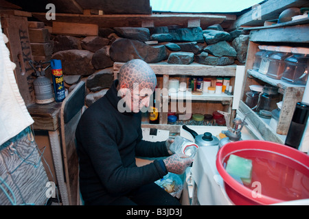 Tattooed  hermit Tom Leppard (aka Leopard Man) makes tea in his secret makeshift underground hideaway shelter on Skye, Scotland Stock Photo