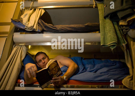 Able-bodied sailor relaxes in his Junior Rating bunk aboard HMS Vigilant, a British Vanguard class nuclear submarine Stock Photo