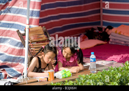 Children doing school homework in a makeshift tent after the earthquake in Sichuan on 12 May 2008, China Stock Photo