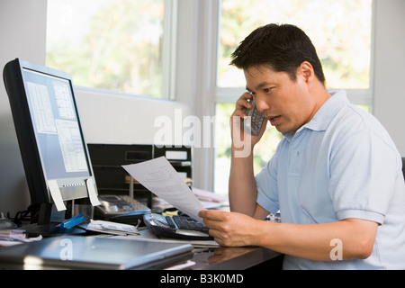 Man in home office with computer and paperwork on telephone Stock Photo