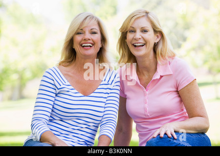 Two women sitting outdoors smiling Stock Photo