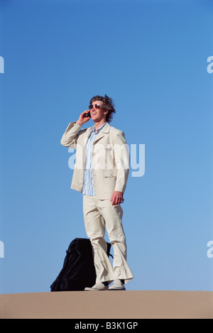 Man outdoors with suitcase using cellular phone Stock Photo