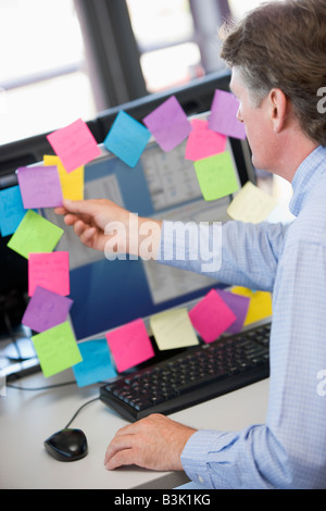 Businessman in office at monitor with notes on it Stock Photo