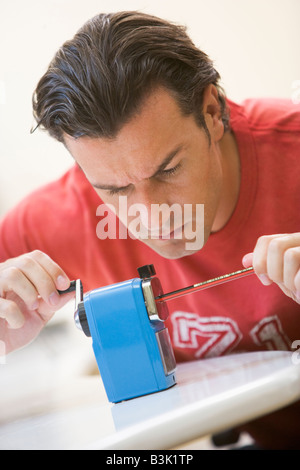Man indoors using pencil sharpener Stock Photo