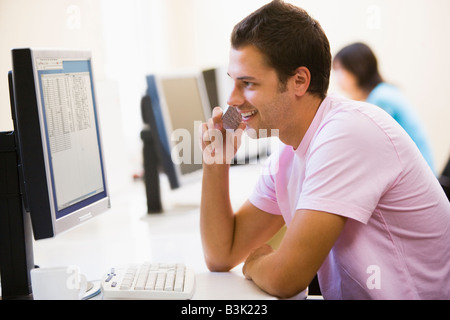 Man in computer room using cellular phone and smiling Stock Photo