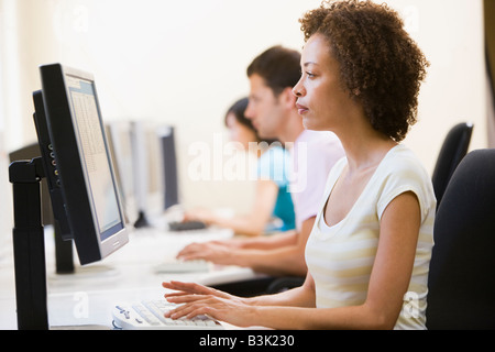 Three people in computer room typing Stock Photo