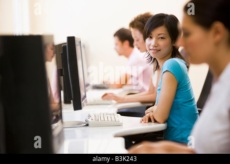 Four people sitting in computer room smiling Stock Photo