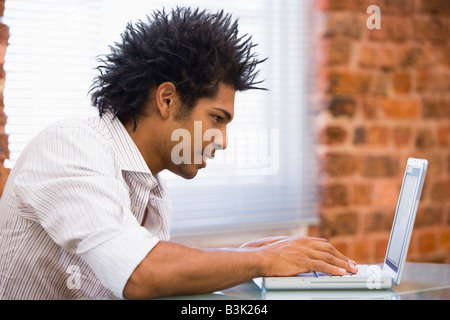 Businessman sitting in office typing on laptop Stock Photo