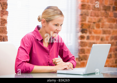 Businesswoman sitting in office using laptop smiling Stock Photo