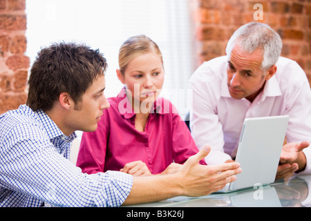 Three businesspeople in office with laptop Stock Photo