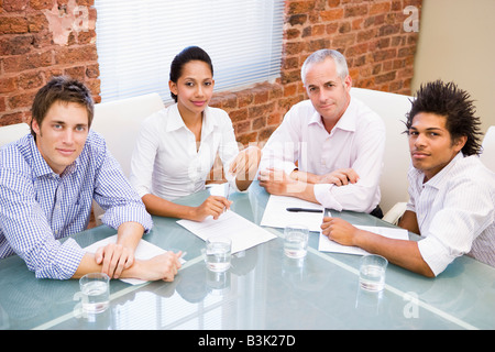 Four businesspeople in boardroom smiling Stock Photo