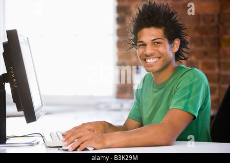 Businessman in office typing on computer smiling Stock Photo